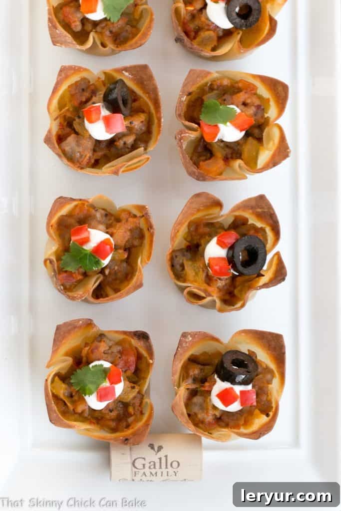 Mini Mexican Tarts - Crispy Shells filled with spiced sausage and cheese create delicious, spicy sausage appetizers Overhead view of Mini Mexican Tarts arranged on a white ceramic tray, garnished and ready to serve.