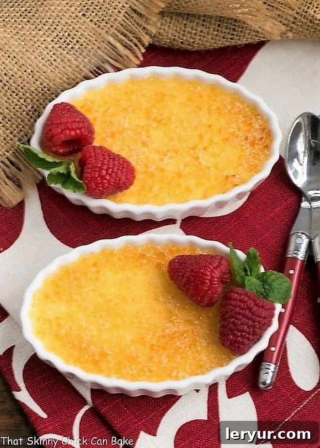 Classic Crème Brûlée - a fabulous vanilla custard topped with a thin layer of brittle, caramelized sugar Two Classic Crème Brûlée with red handled spoons..