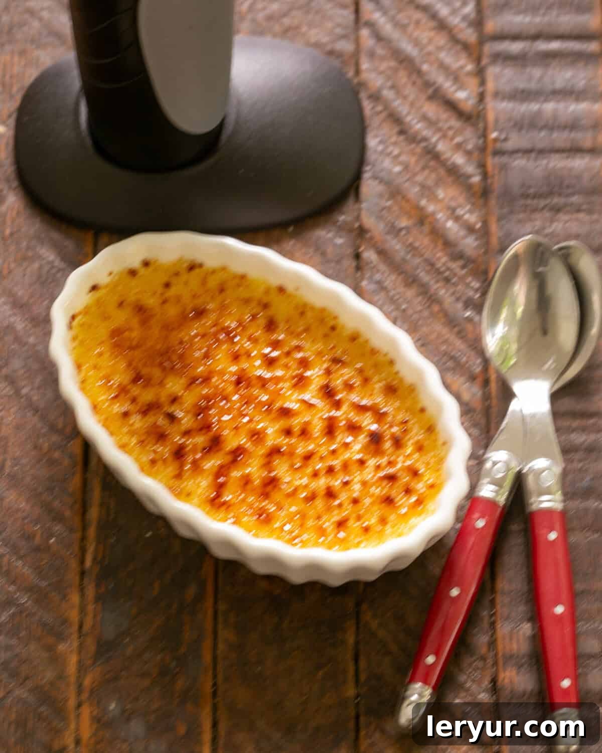 The Ultimate Crème Brûlée Guide 9 Finished creme brulee with 2 red handle spoons.