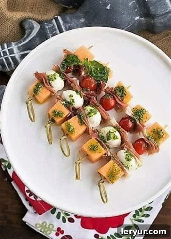 Easy Melon and Prosciutto Skewers - Ideal for Summer Parties Rows of Melon and Prosciutto Skewers artfully arranged on a pristine white cake stand, highlighting their elegant presentation.