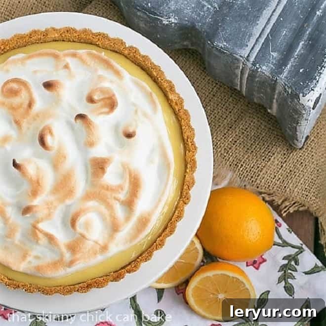 Overhead view of a beautiful Meyer Lemon Tart with Meringue Topping on a white cake stand, highlighting the intricate swirls of the toasted meringue.