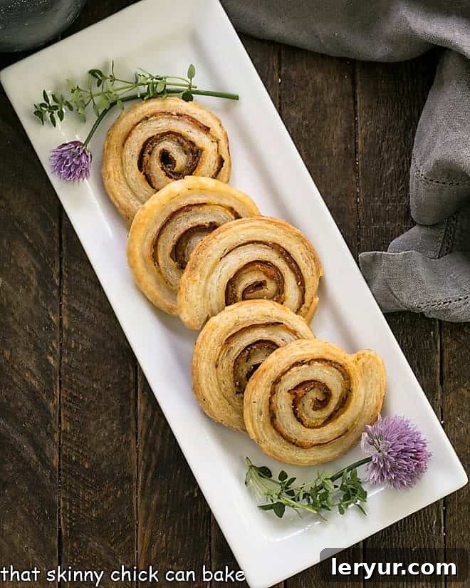 Overhead view showcasing a generous spread of freshly baked pepperoni pinwheels arranged on a pristine white ceramic tray, emphasizing their golden color and intricate spirals.