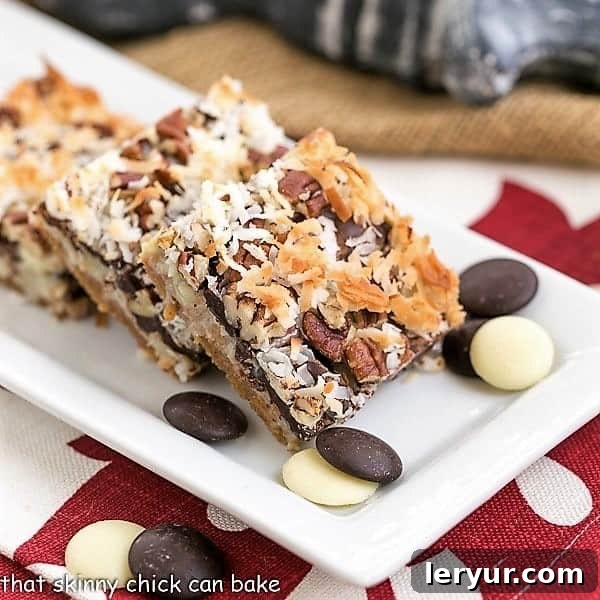 The Best Seven Layer Bars - Graham cracker crust layered with 3 types of chocolate chips, sweetened condensed milk, coconut and pecans! The Best Magic Cookie Bars on a rectangular, white tray.