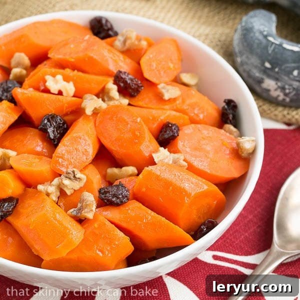 Orange Glazed Carrots in a white serving bowl, garnished with walnuts and dried cranberries
