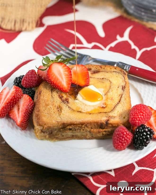 Overnight Cinnamon Bread French Toast - a scrumptious, make ahead brunch dish! Overnight Cinnamon Bread French Toast with a generous drizzle of golden maple syrup on a white plate, ready to be enjoyed.