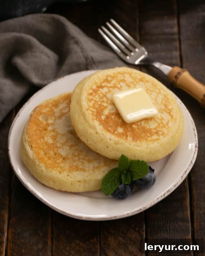 Fluffy Buttermilk Pancakes 6 Two golden-brown buttermilk pancakes served on a simple white plate, ready for toppings, showcasing the finished product of the recipe.