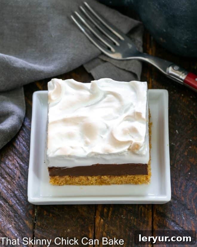 Gooey Smores Fudge Bars 2 A single S'mores Fudge Bar resting on a small white square ceramic plate, showcasing its distinct layers.