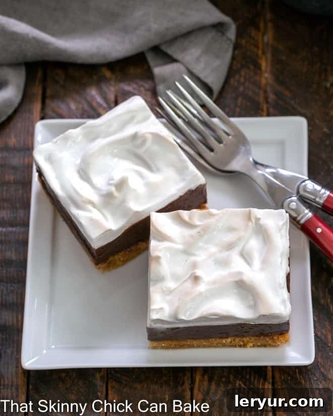 Gooey Smores Fudge Bars 5 Two S'mores Fudge Bars on a square white plate, accompanied by two forks with red handles, ready to be enjoyed.