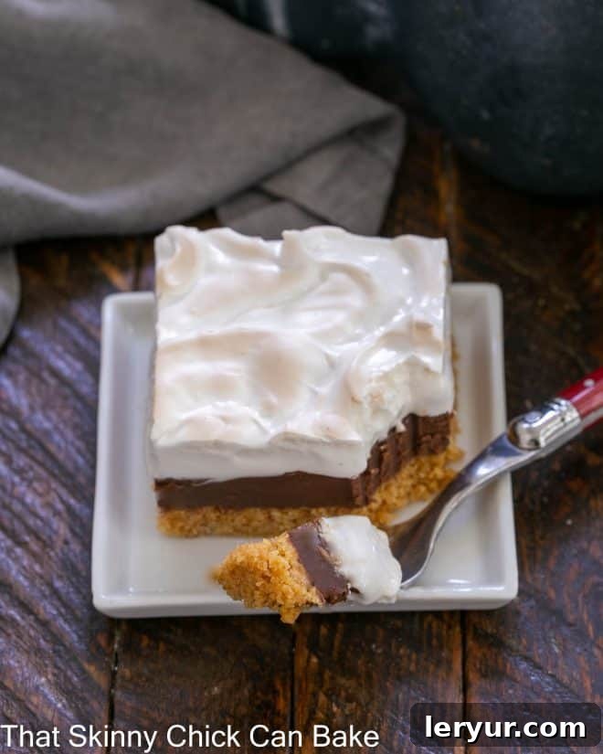 Gooey Smores Fudge Bars 6 A S'mores Fudge Bar on a white plate with a piece lifted on a red handled fork, emphasizing the gooey texture.