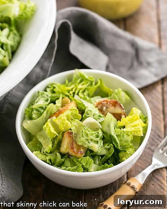 Caesar Salad Recipe in a small white salad bowl with a bamboo handled fork.