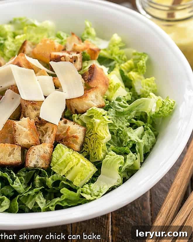 Close view of undressed Caesar salad in a white serving bowl.