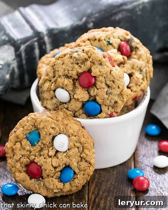 Patriotic Monster Cookie Recipe - Peanut butter oatmeal cookies chock-full of M&M's and chocolate chips Peanut Butter Oatmeal Cookies with M&Ms in a small white bowl surrounded by patriotic colored M&Ms