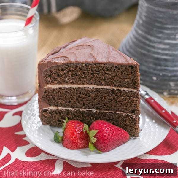 A beautifully decorated slice of Chocolate Layer Cake with creamy Vanilla Buttercream on a pristine white plate, garnished with fresh, vibrant strawberries, highlighting its rich layers and tempting texture. This decadent dessert is perfect for any celebration.
