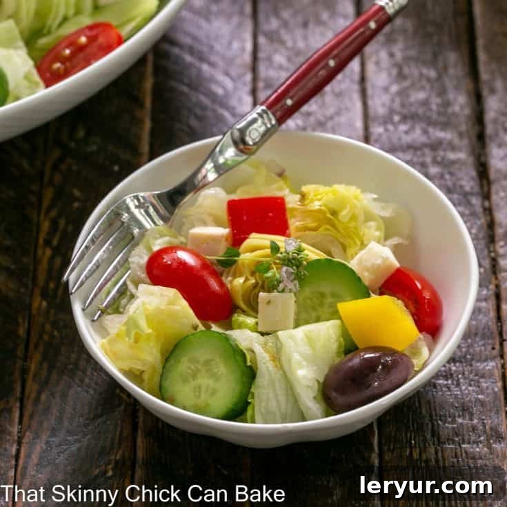 Small white bowl of Greek salad with a red handled fork