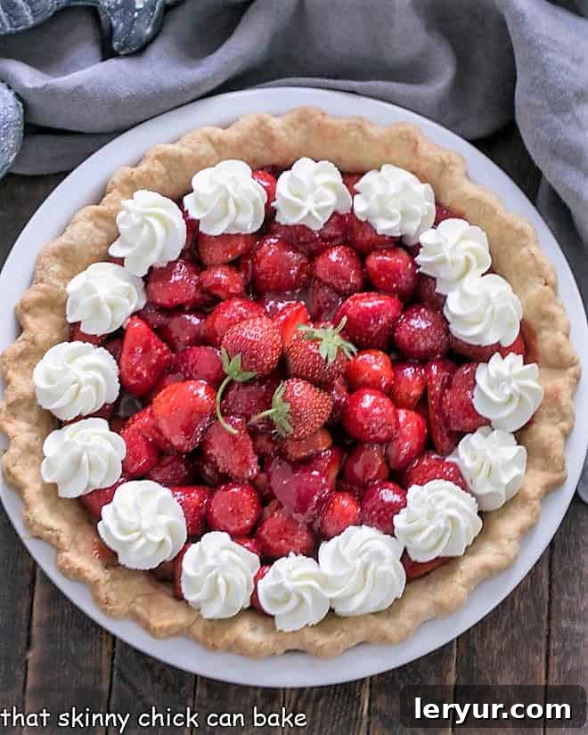 Juicy Strawberry Pie A Slice of Summer 2 Overhead view of a fresh strawberry pie garnished generously with whipped cream, highlighting its inviting appeal
