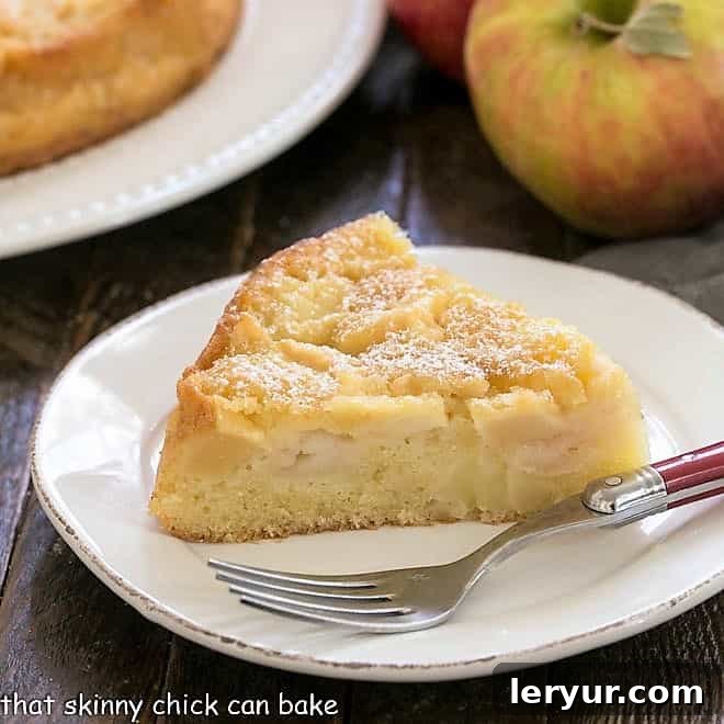 A perfectly baked slice of French apple cake resting on a pristine round white plate, ready to be enjoyed.