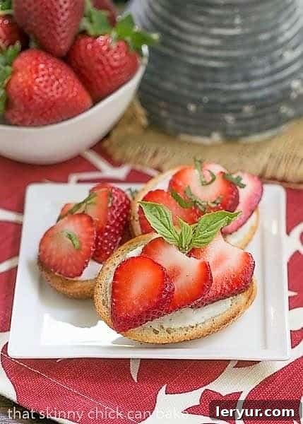 Strawberry Basil Crostini - A spectacular out of the ordinary appetizer! Strawberry Basil Crostini on a white appetizer plate with a bowl of strawberries