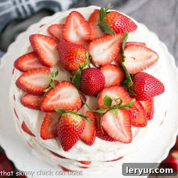 Fresh Strawberry Meringue Cake - A luscious dessert with layers of baked meringue, fresh strawberries and mascarpone whipped cream! Overhead view of a beautifully assembled Fresh Strawberry Meringue Cake on a pristine white cake stand, showcasing its delicate layers and vibrant red berries.