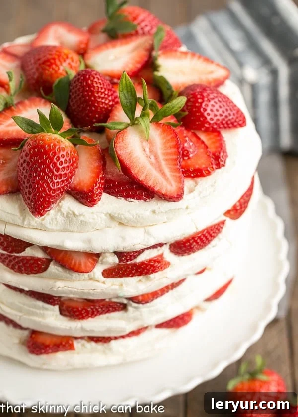 Fresh Strawberry Meringue Cake - A luscious dessert with layers of baked meringue, fresh strawberries and mascarpone whipped cream! A delectable side view of the Fresh Strawberry Meringue Cake, revealing its distinct layers of crispy meringue, creamy filling, and vibrant strawberries, ready to be served.