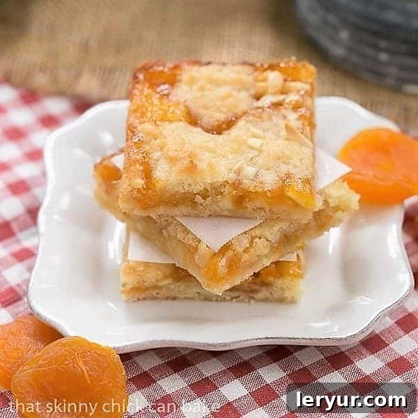 Coconut Apricot Bars - Scrumptious layered bars with coconut, almonds, and apricot preserves Stacked Coconut Apricot Bars on a small white plate, showcasing their inviting layers.