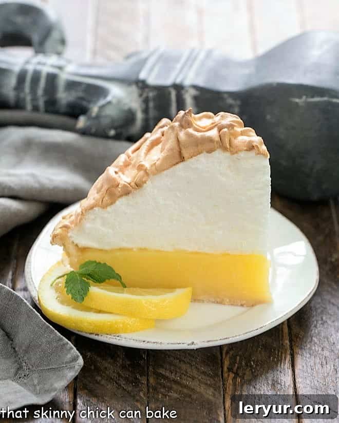 Mile High Lemon Meringue Pie - Luscious lemon filled pastry crust topped with a pillow of fluffy meringue Slice of Mile High Lemon Meringue Pie on a white plate
