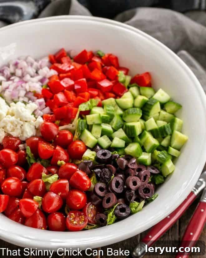 A beautifully presented Mediterranean Chopped Salad in a rustic serving bowl, showcasing a medley of vibrant ingredients like tomatoes, cucumbers, olives, and feta cheese, ready to be enjoyed.