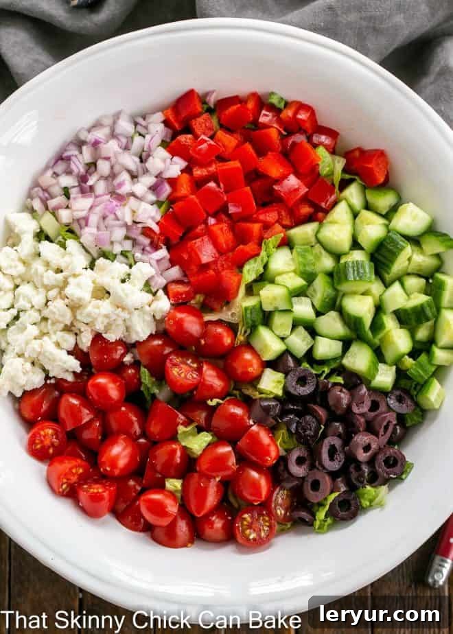 An overhead view of a vibrant Mediterranean Chopped Salad, meticulously arranged to display all its fresh, colorful ingredients including crisp lettuce, red onions, bell peppers, and olives, making a feast for the eyes.
