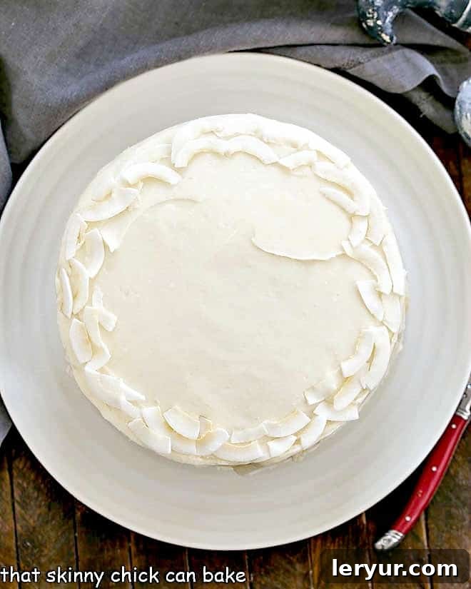 Decadent Italian Cream Cake 4 An inviting overhead view of a fully frosted Italian Cream Cake, topped with delicate coconut flakes, resting on a pristine white cake plate, ready to be served.