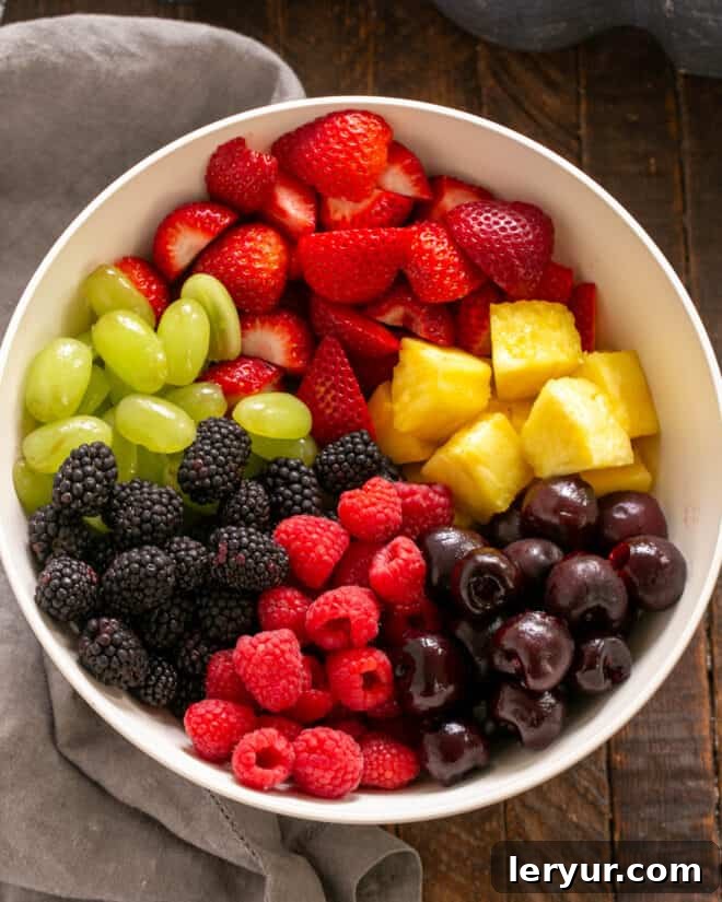 Zesty Honey-Lime Fruit Medley 4 Adding a vibrant variety of fresh fruits to a large mixing bowl.