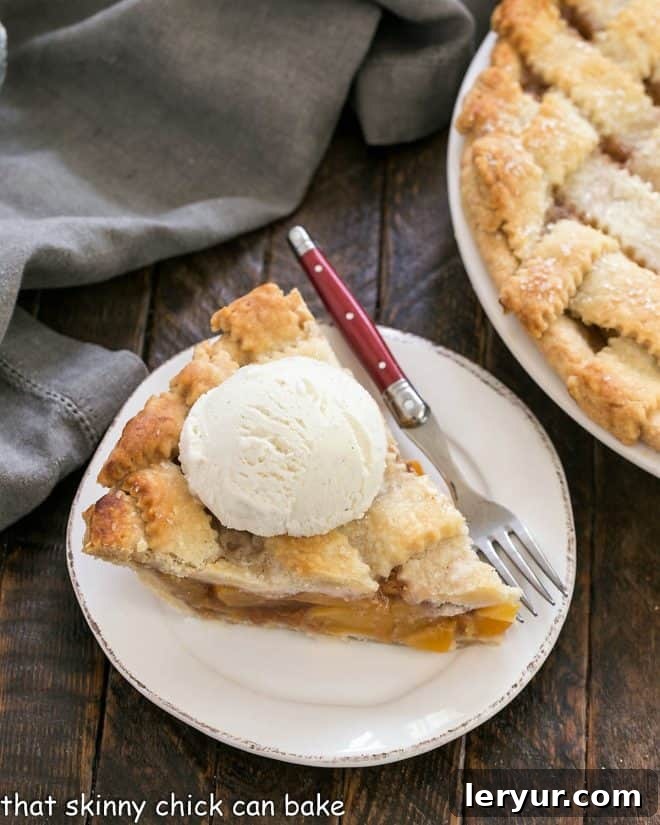 Sweet Summer Peach Lattice Pie 8 Slice of peach pie on a dessert plate with a red handled fork.