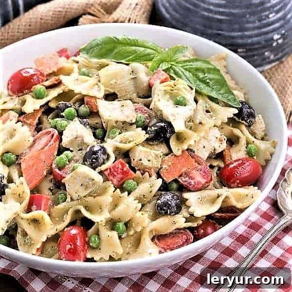 Vibrant Pesto Pasta Salad artfully arranged in a flat white serving bowl, ready to be enjoyed with a silver serving spoon resting beside it.