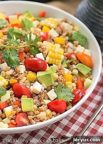Summer Farro Salad - Farro, cucumbers, avocados, tomatoes and fresh corn dressed with a simple lime vinaigrette Refreshing Summer Farro Salad with corn, avocado, and cotija in a white bowl on a checkered napkin