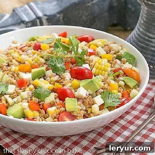 Summer Farro Salad - Farro, cucumbers, avocados, tomatoes and fresh corn dressed with a simple lime vinaigrette Close-up of a colorful Summer Farro Salad in a white serving bowl, showcasing fresh ingredients