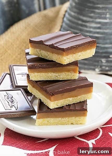 Ganache Topped Caramel Bars stacked high on a white plate over a red and white napkin, inviting a taste.