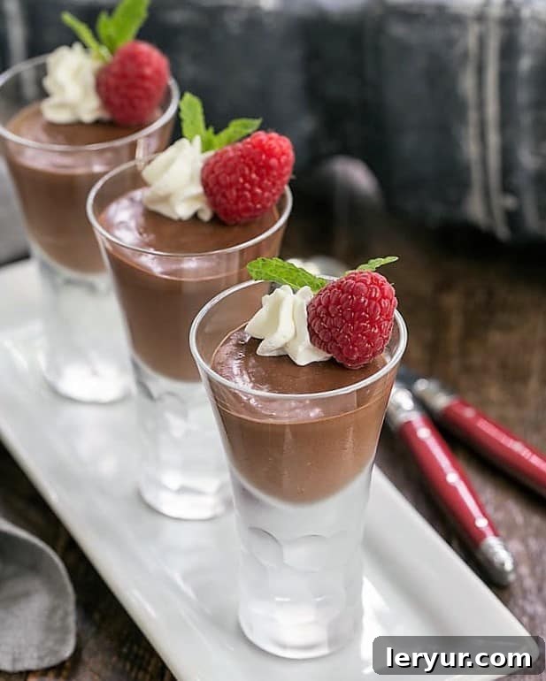 Blender Chocolate Mousse served in a glass, topped with whipped cream and a sprinkle of chocolate shavings, on a white tray.