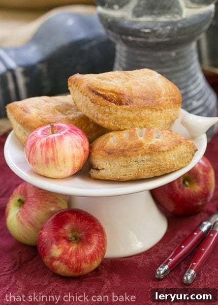 Chaussons aux Pommes - Easy delicious apple turnovers! Chaussons aux Pommes on a ceramic tray with apples.