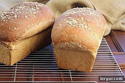 Two golden-brown loaves of homemade honey oatmeal bread cooling on a wire rack.