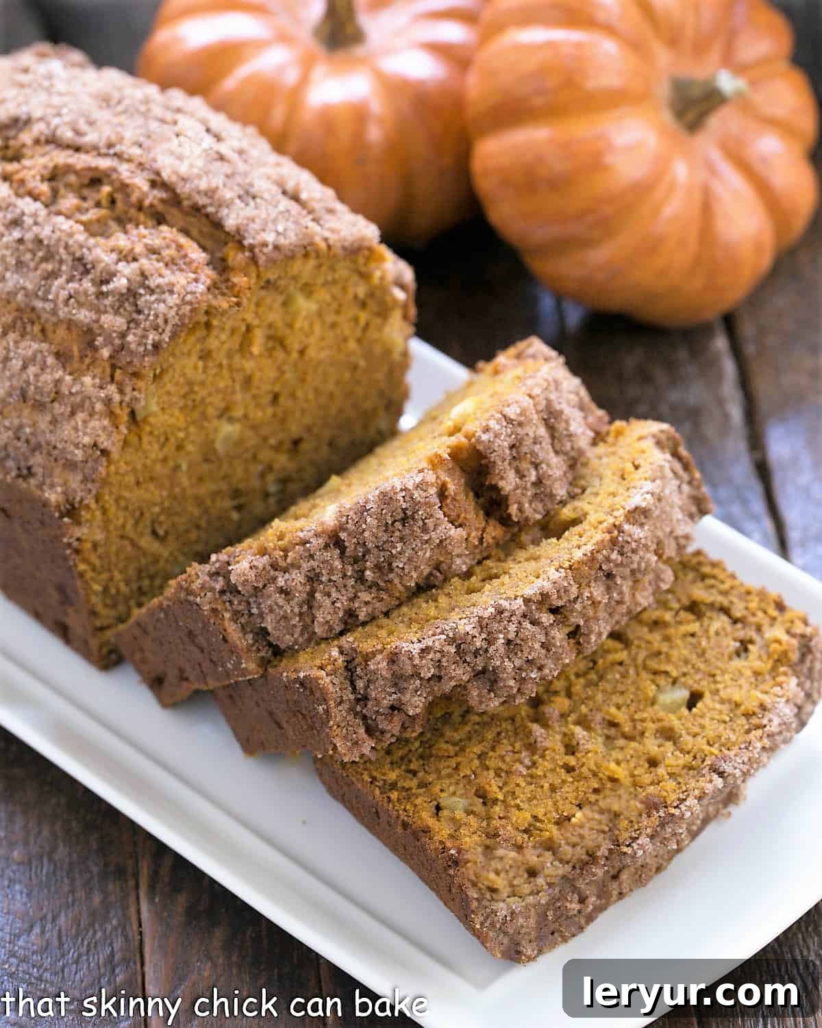Pumpkin Bread with Apples sliced on a white ceramic tray with 2 mini pumpkins.