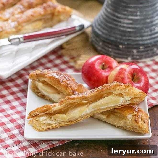 Two generous slices of a golden Maple Glazed Apple Tart, showcasing the flaky puff pastry, creamy filling, and neatly arranged apple slices, served on a square white plate, ready to be enjoyed.