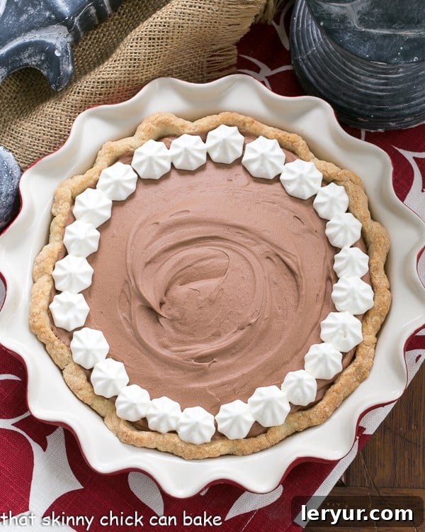 Classic French Silk Pie garnished with whipped cream in a red pie plate overhead view. Decorated with swirls of whipped cream and chocolate shavings.