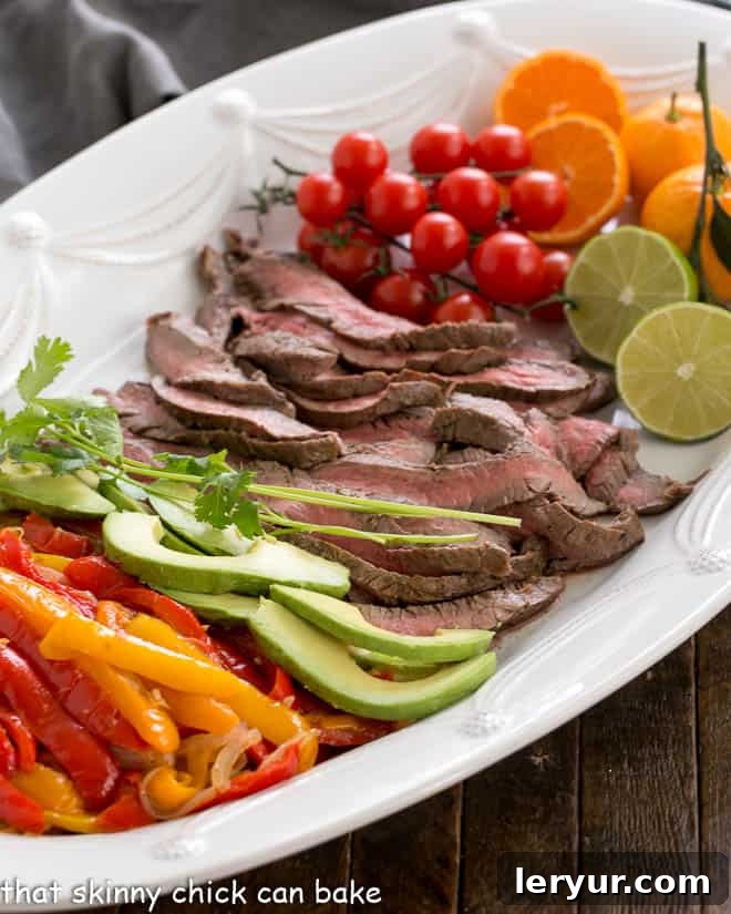 Flank Steak Fajitas and toppings on a white platter, showcasing a healthy and delicious meal.