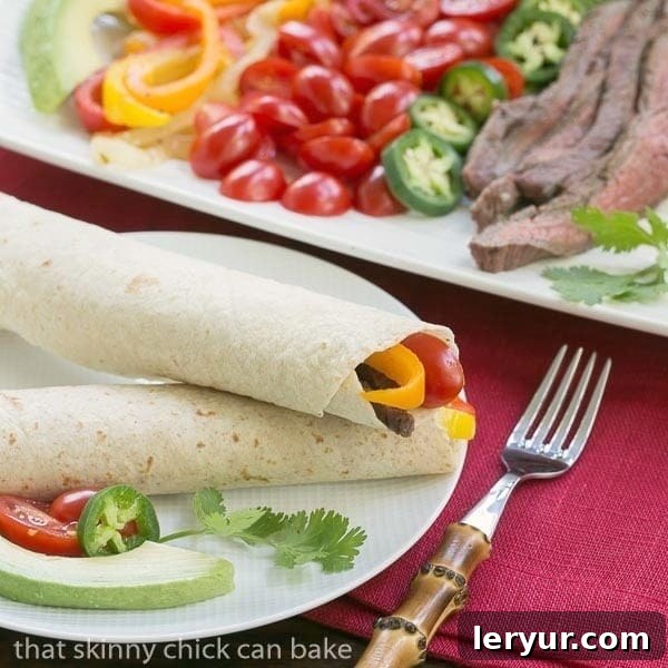 Two Flank Steak Fajitas on a white dinner plate, garnished with fresh cilantro and ready for enjoyment.