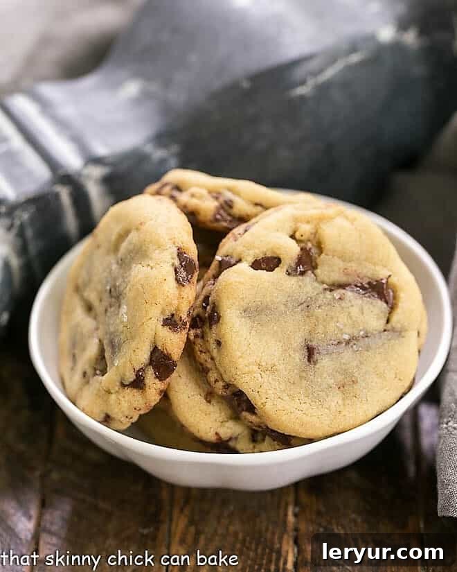 Layered Chocolate Chip Cookies - Dark brown sugar and layers of bittersweet chocolate shards make these a one-of-a-kind chocolate chip cookie! Layered Chocolate Chip Cookies arranged beautifully in a white bowl, ready to be enjoyed.