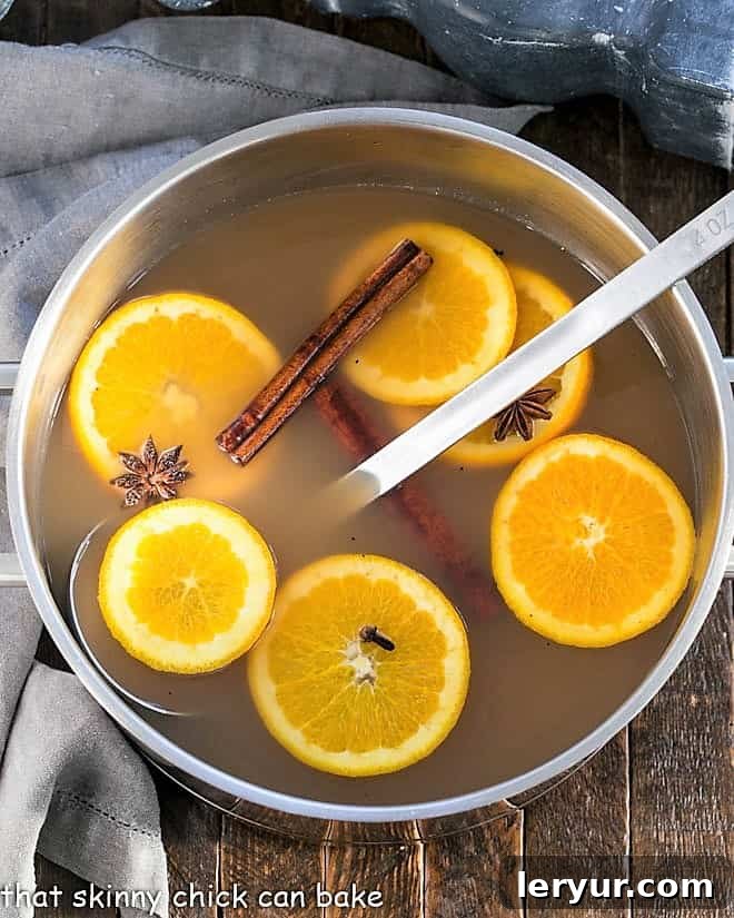 Mulled Apple Cider simmering in a large stock pot with orange slices and spices.