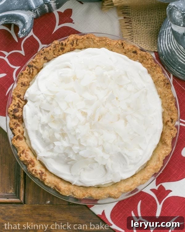Perfectly Layered Coconut Cream Pie Close-up of a slice of Coconut Cream Pie, showing the layers of flaky crust, thick coconut custard, and fluffy whipped cream, topped with toasted coconut.