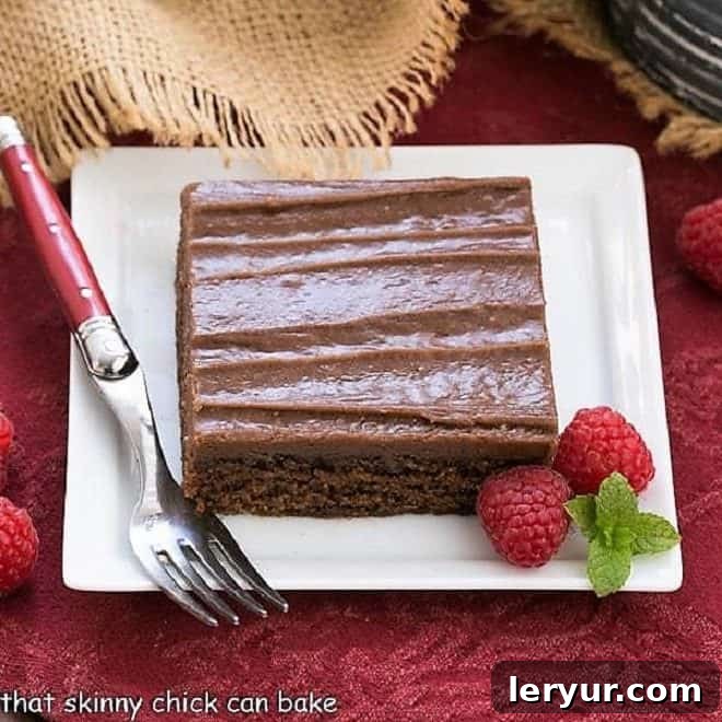 Decadent Chocolate Sheet Cake slice on a square white plate with fresh raspberries, ready to be enjoyed.