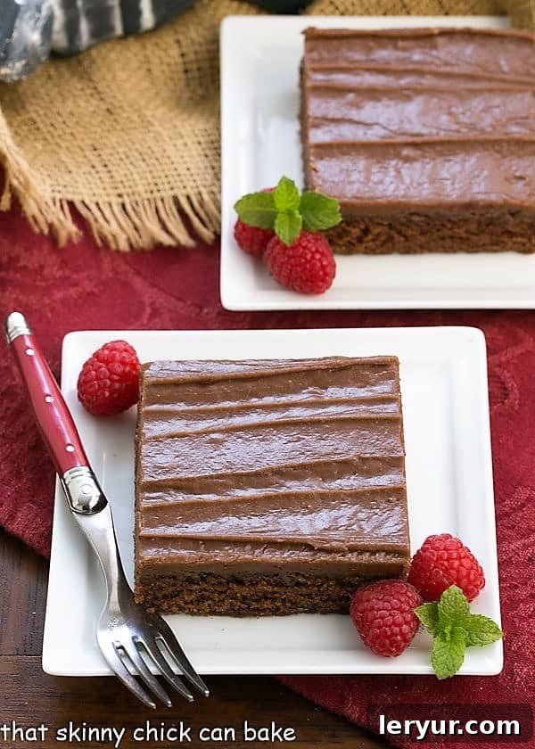 Multiple slices of rich Texas Sheet Cake displayed on square white plates with fresh raspberries, highlighting its suitability for sharing.