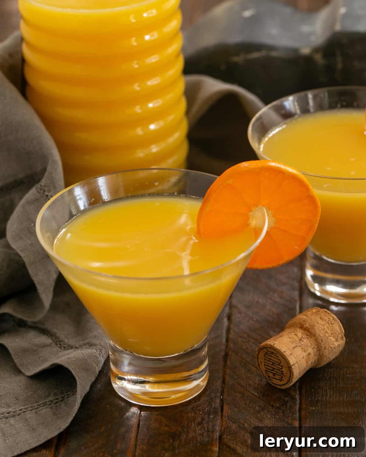 Grand Marnier Mimosas - The classic orange juice and champagne cocktail with the optional splash of Grand Marnier Grand Mimosas in elegant Viski Glasses in front of a pitcher of mimosas, ready for serving.