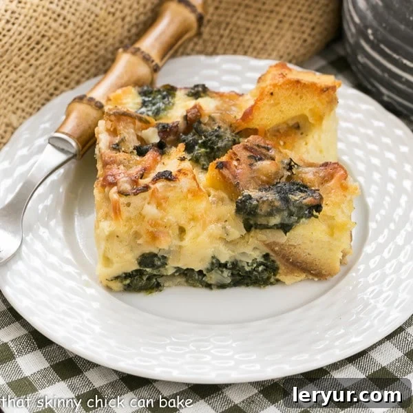 Gruyere Spinach Strata slice on a white plate with a bamboo handle fork.