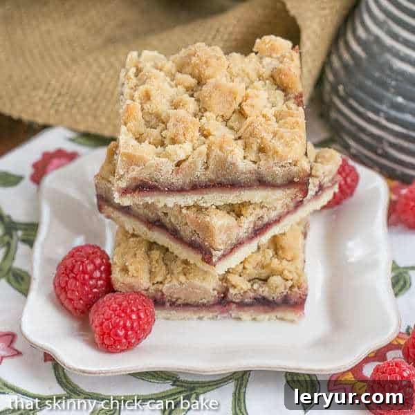 A stack of golden-brown Raspberry Crumb Bars with visible layers of crust, jam, and streusel